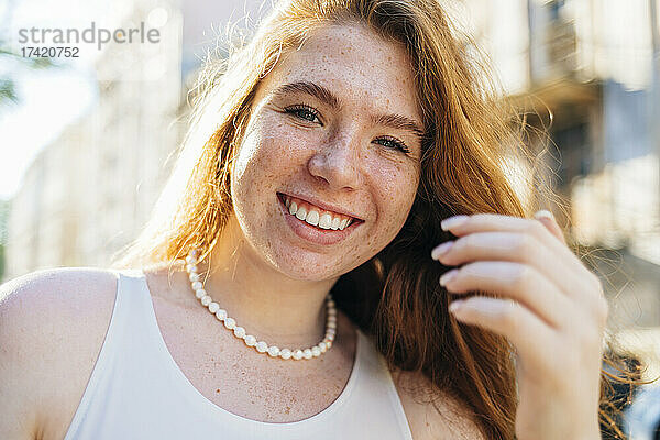 Glückliche junge Frau mit Sommersprossen und Perlenkette