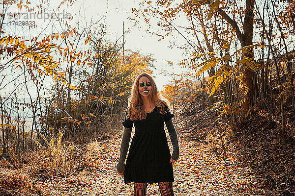 Lächelnde Frau mit Halloween-Make-up steht im Herbst im Wald