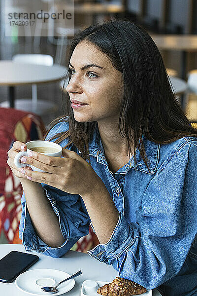 Nachdenkliche Freiberuflerin trinkt Kaffee im Café