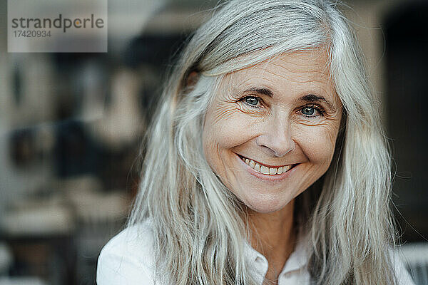 Lächelnde reife Frau mit grauen Haaren im Café