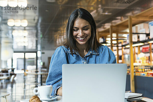 Lächelnde Geschäftsfrau  die im Café am Laptop arbeitet