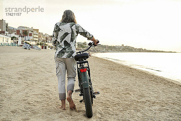 Reifer Mann fährt mit dem Fahrrad auf Sand am Strand