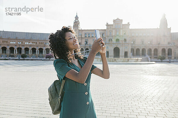 Lächelnde Touristin fotografiert mit dem Smartphone an der Plaza De Espana  Sevilla  Spanien
