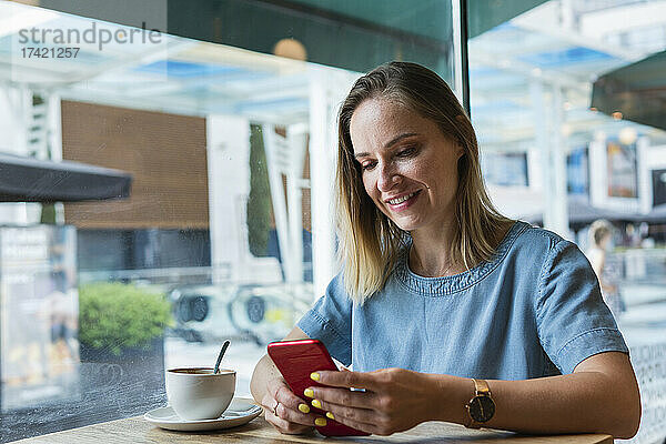 Blonde Freiberuflerin benutzt Mobiltelefon im Café