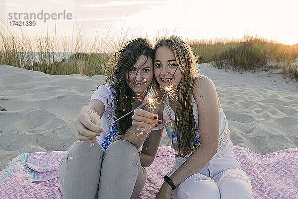Junge Freundinnen brennen Wunderkerzen am Strand