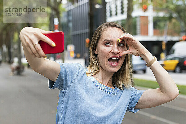 Fröhliche Geschäftsfrau  die unterwegs ein Selfie mit dem Mobiltelefon macht
