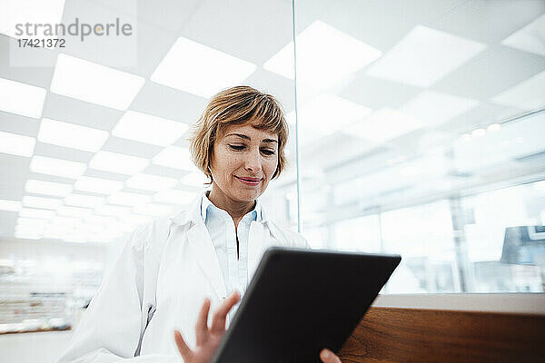 Lächelnde Ärztin mit digitalem Tablet in der Apotheke