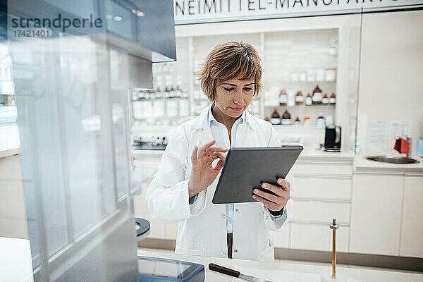 Apothekerin nutzt digitales Tablet  während sie im Labor steht