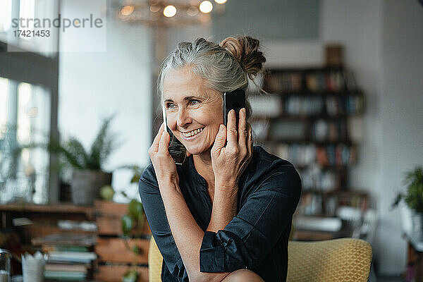 Lächelnde Geschäftsfrau  die im Café mit Mobiltelefonen spricht