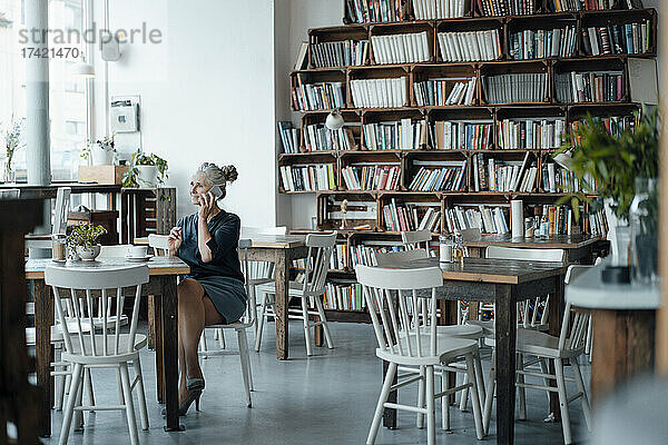 Geschäftsfrau telefoniert  während sie im Café sitzt