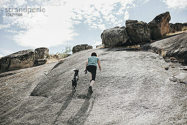 Frau mittleren Alters und Hund laufen auf einer Felslandschaft