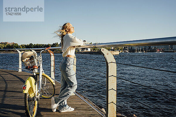 Frau mit Fahrrad steht am Geländer an der Promenade