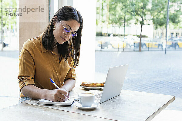 Geschäftsfrau schreibt Tagebuch  während sie im Café arbeitet