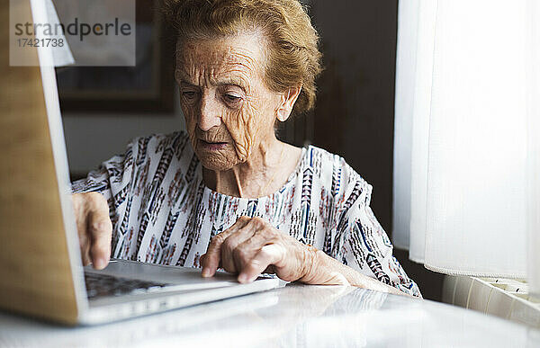 Ältere Frau mit kurzen Haaren benutzt Laptop zu Hause