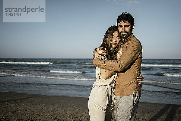 Paar umarmt sich  während es am Strand steht