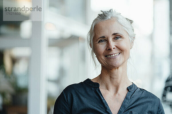 Lächelnde Frau mit grauen Haaren im Café