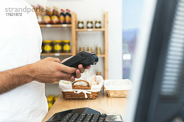 Männlicher Ladenbesitzer benutzt Kreditkartenlesegerät am Schalter