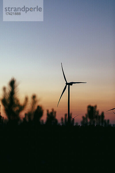 Silhouette einer Windkraftanlage  die in der Abenddämmerung vor klarem Himmel steht