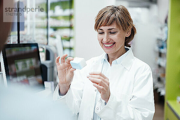 Lächelnde Apothekerin erklärt männlichen Kunden im Sanitätshaus Medikamente
