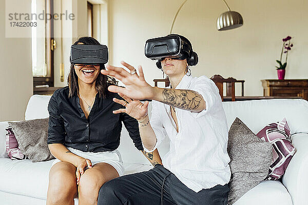 Junge Lesben gestikulieren  während sie zu Hause die virtuelle Realität über Headsets genießen