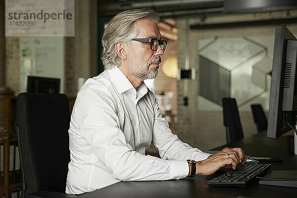 Geschäftsmann mit grauen Haaren arbeitet im Büro am Computer