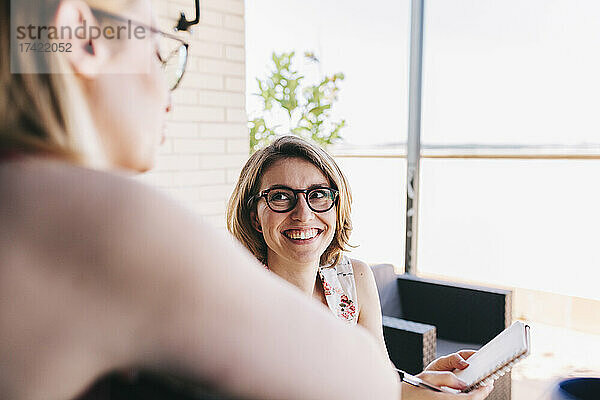 Lächelnde Geschäftsfrau zeigt einem Kollegen auf dem Dach einen Notizblock