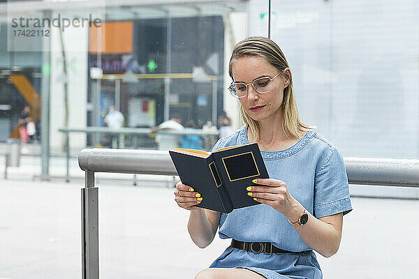Blonde Geschäftsfrau mit Brille liest Buch