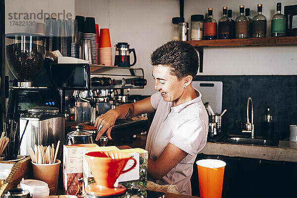 Weibliche Barista bereitet Kaffee zu  während sie im Café arbeitet