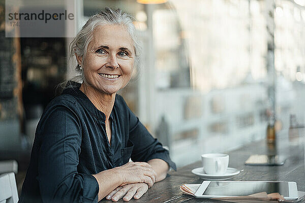 Lächelnde Geschäftsfrau sitzt am Tisch im Café