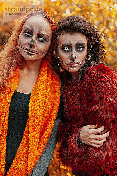 Freundinnen mit Halloween-Make-up und Kostüm stehen im Wald