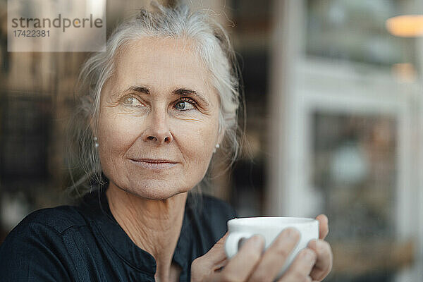 Reife Frau hält Tasse im Café