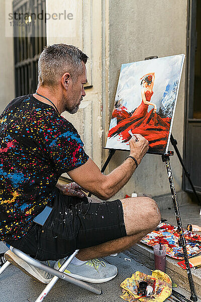 Männlicher Künstler malt Frau auf Leinwand am Fußweg