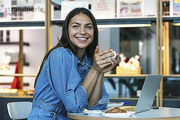 Lächelnde Frau mit Laptop beim Kaffee im Café