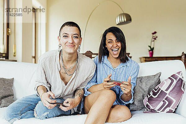 Fröhliche junge Freundinnen spielen zu Hause im Wohnzimmer Videospiele