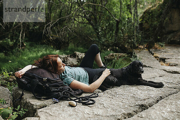 Mitte erwachsene Frau liegt mit Hund auf Fußweg im Wald