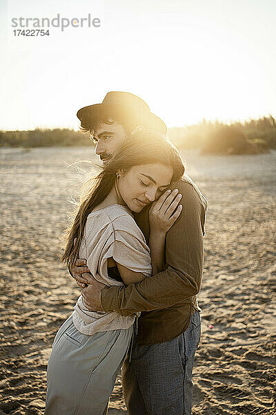 Paar umarmt sich  während es am Strand steht