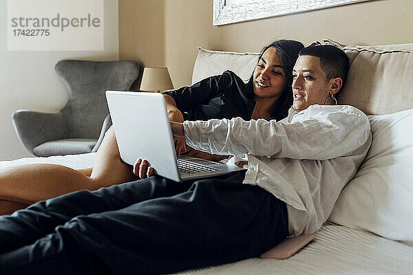 Lesben teilen sich Laptop  während sie zu Hause im Bett liegen