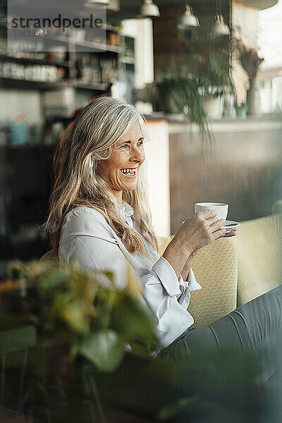 Fröhliche Geschäftsfrau trinkt Kaffee  während sie im Café sitzt