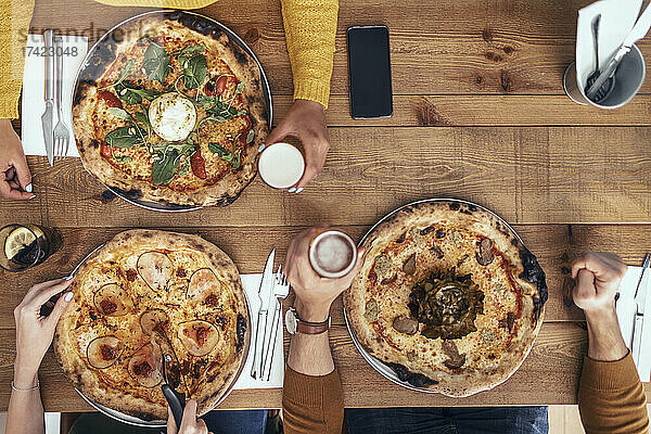 Männliche und weibliche Freunde sitzen mit Pizza am Tisch im Restaurant