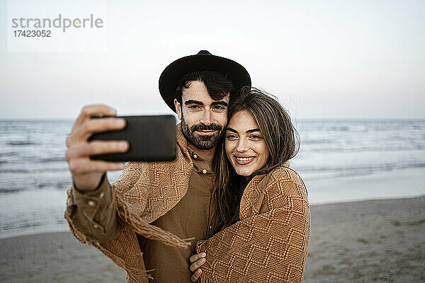 Freund macht Selfie mit Freundin per Handy am Strand