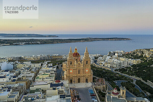 Malta  Nordregion  Mellieha  Luftaufnahme der Pfarrkirche der Geburt der Jungfrau Maria in der Abenddämmerung mit der Ghadira-Bucht im Hintergrund