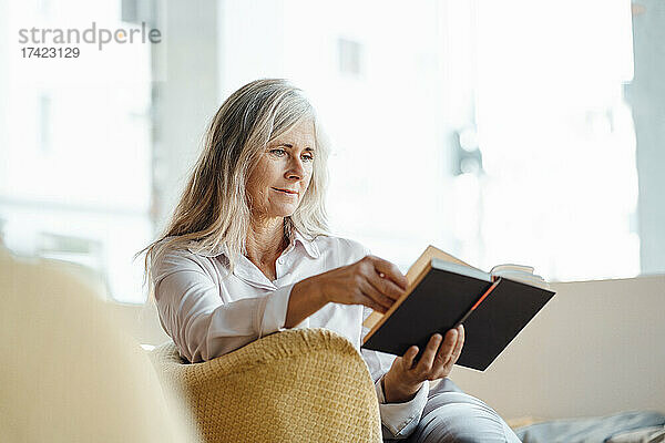 Reife Frau liest Buch  während sie im Café sitzt