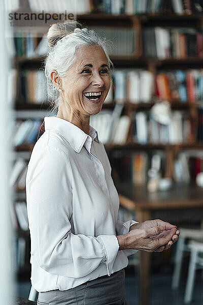 Fröhliche Frau mit grauen Haaren steht im Café
