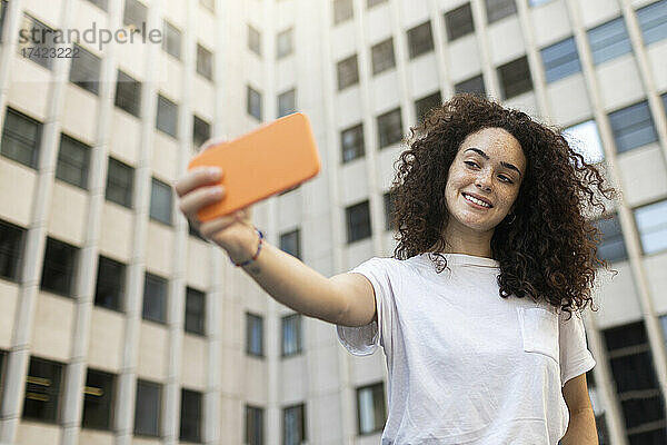 Frau macht Selfie mit Smartphone vor Gebäude