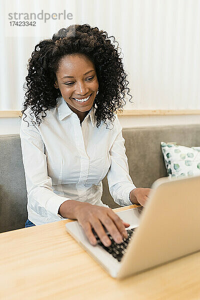 Geschäftsfrau lächelt bei Videoanruf über Laptop im Café