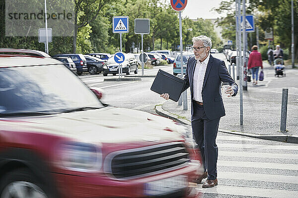 Schockierter älterer männlicher Berufstätiger überquert rasendes Auto