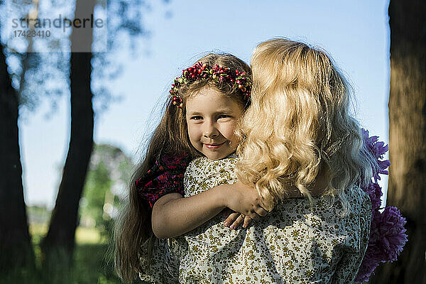 Lächelnde Tochter umarmt Mutter im Garten