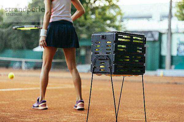 Tennisbälle in einer Box  im Hintergrund trainiert eine Sportlerin