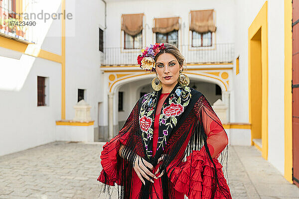 Frau in traditioneller Kleidung steht an der Plaza de Toros de la Real Maestranza de Caballeria de Sevilla  Spanien