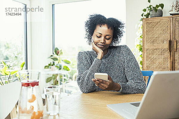 Afro-Freiberuflerin nutzt Smartphone im Heimbüro